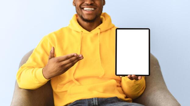 Check This Out. Unrecognizable Black Man Showing Tablet Computer With Empty Screen Recommending Website Sitting On Gray Background. Mockup For Application Advertisement. Selective Focus, Panorama photo