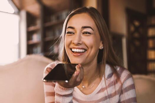 de cerca retrato de sonriente mujer participación Teléfono móvil cerca boca utilizando móvil voz reconocimiento o digital asistencia aplicación Hablando con virtual asistente, grabación mensaje hablando en teléfono inteligente foto