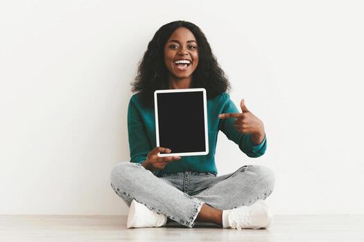 Attractive young black woman showing modern digital tablet with empty screen, newest pad with blank display, mockup, white studio background, various mobile apps for tablets concept, copy space photo