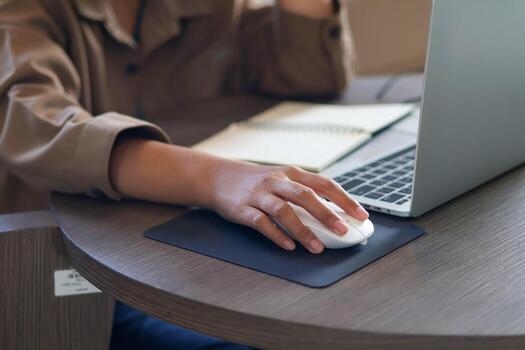 Use your hand to hold the white mouse to view information on the laptop. photo