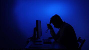 une homme séance à une bureau dans de face de une ordinateur video