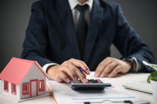 un hombre en un traje es utilizando un calculadora a calcular el valor de su casa foto