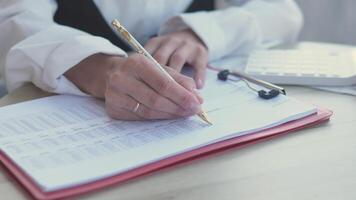 ein Nahansicht Aussicht von Hände sorgfältig Schreiben Anmerkungen auf ein dokumentieren, betonen ein klar, produktiv Büro Umgebung video