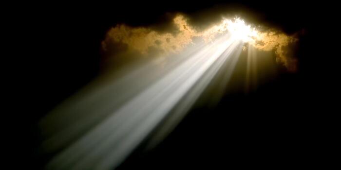 Sun rays stream powerfully through a dark cloudy sky creating a dramatic heavenly light effect photo