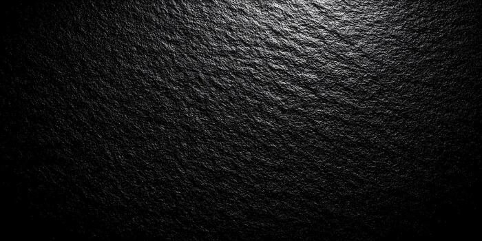 A dark textured surface with subtle light creating an abstract natural background photo