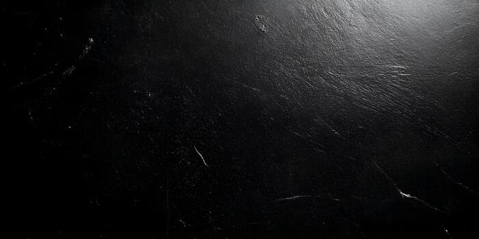A dark textured surface with subtle light reflections creating a mysterious background photo