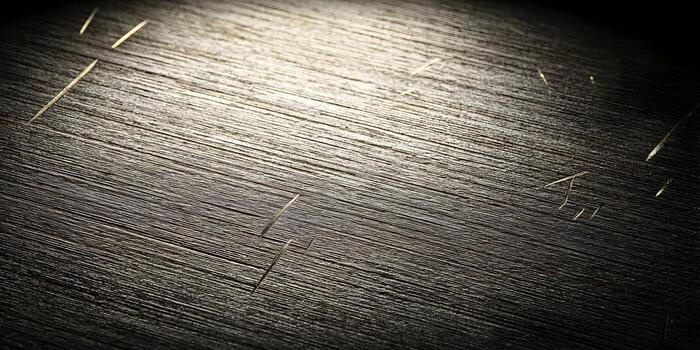 Dark textured surface with fine parallel lines and subtle scratches illuminated by light photo
