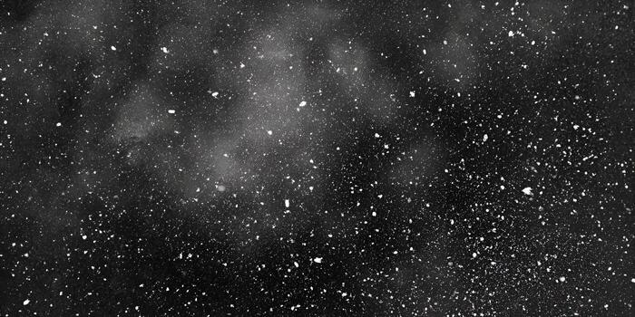White particles fall against a dark black background creating an abstract snowy or dusty effect photo