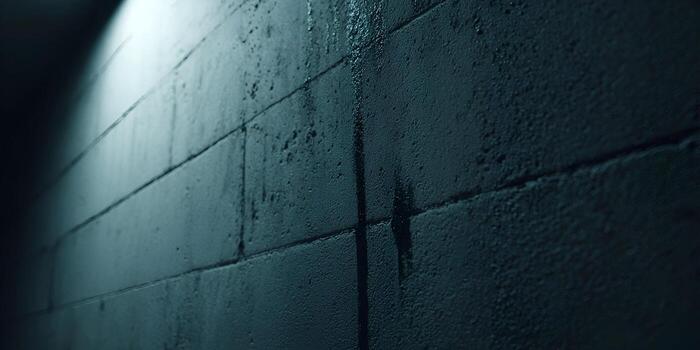 un oscuro mojado texturizado hormigón bloquear pared con agua rayas es iluminado por un duro ligero creando un temperamental antecedentes foto