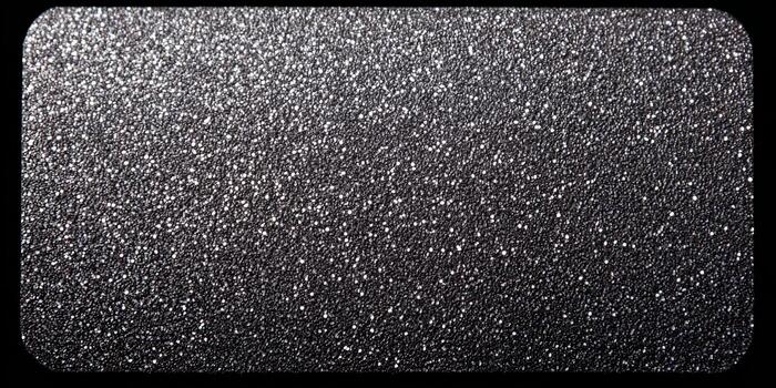A dark textured surface sparkles with numerous white and silver glitter particles creating an abstract background photo