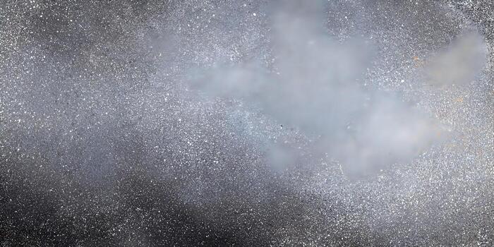 A dark charcoal gray surface is covered with a fine speckle texture creating a grunge background photo