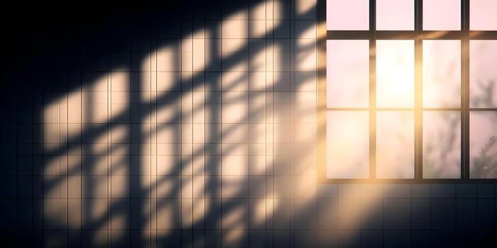 Sunlight streams through a window casting grid and tree branch shadows on a dark tiled wall photo