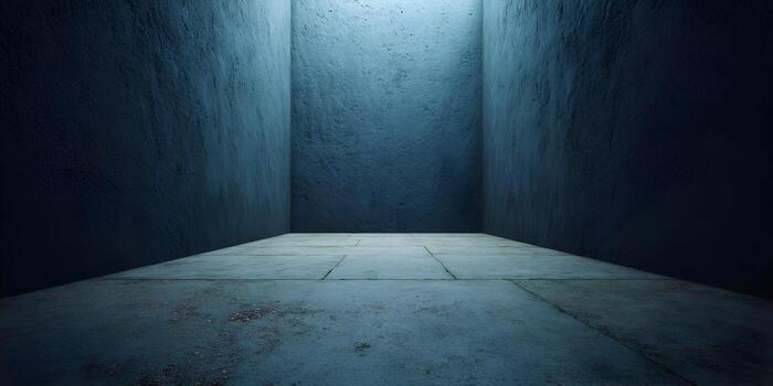 An empty concrete room with textured dark blue walls and a tiled floor illuminated by an overhead light source photo