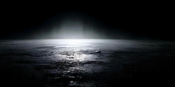 A dramatic spotlight illuminates a desolate textured ground in a dark empty space photo