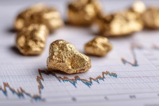 Golden nuggets scattered on a financial graph, highlighting the intersection of precious metal investment and market analysis. The focus is on the gold pieces with background blur photo