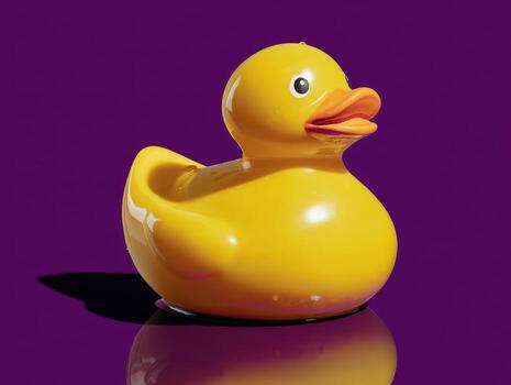 Yellow rubber duck with a shiny surface and an orange beak stands on a reflective surface. Its round shape and bright color contrast against the plain background photo