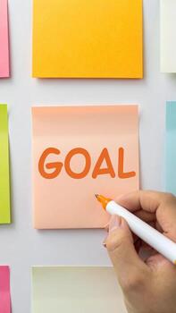 Hand writing goal on sticky note with marker photo