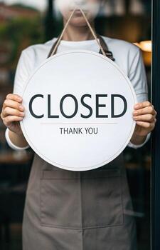 Person holding closed sign in front of store photo