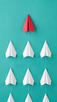 Red paper airplane leading white paper airplanes photo