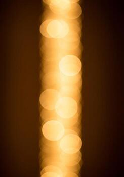 Abstract Golden Bokeh String Vertical Against Brown Background Festive Illumination photo