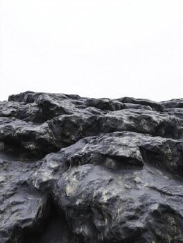 Dark Rocky Surface with Textured Formation Against a Minimalistic White Sky Backdrop photo