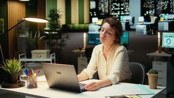 entreprenör väger på en komplex problem i en mörk kontor sent på natt, strategisering och skriver alternativ på bärbar dator. sökande en logisk lösning genom försiktig koncentration. kamera a. video