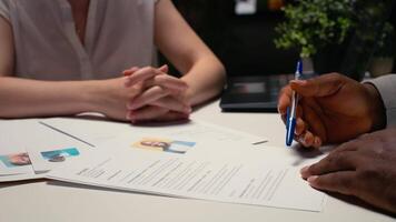 Close up of a CV resume on the table during detailed job interview with applicant and HR manager, reviewing the candidate qualifications and work experience for the selection process. Camera A. video