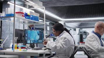 nero scienziato l'esame campioni sotto microscopio nel un' moderno laboratorio. ricerca opera integra biotecnologia, molecolare scienza e Avanzate diagnostica per forma medico scoperta. telecamera un. video