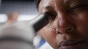 vicino su di scienziato collocazione vassoio campione sotto microscopio nel chimica laboratorio. ricerca opera integra biotecnologia, molecolare scienza e Avanzate diagnostica per forma medico scoperta. telecamera b. video