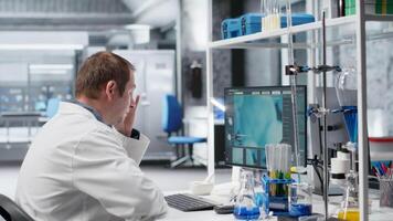 missnöjd forskare kämpar till figur ut komplicerad experimentera data i laboratorium. förvirrad och misslyckad man som handlar om med utmaningar av bioteknik och genetik forskning. kamera b. video