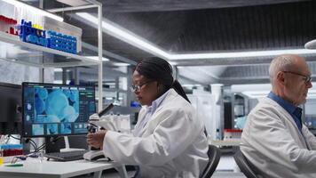 africano americano químico analisando molecular amostras dentro uma laboratório, usando profissional microscópio. cuidados de saúde inovação e bioquímica experimentos representar científico método e descoberta. Câmera uma. video