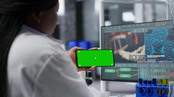 svart expert- använder sig av krom nyckel skärm för laboratorium studie på smartphone, Arbetar med experimentera data för molekyl vetenskap. Avancerad forskning, farmakologi och bioteknik upptäckt. kamera b. video
