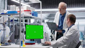 verde schermo su computer Schermo con colleghi Lavorando nel biotecnologia laboratorio, utilizzando laboratorio analisi, bioingegneria e assistenza sanitaria tecnologia. progresso nel farmaceutico scienza. telecamera b. video