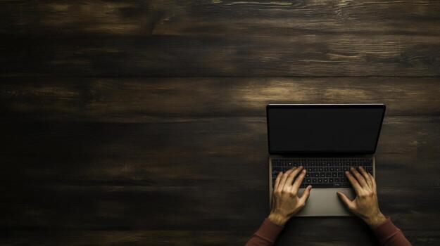 Hands Typing on Laptop with Empty Screen on a Dark Wooden Table Surface photo