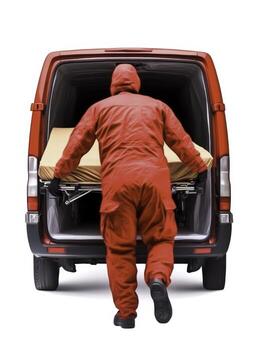 Emergency Response Worker in Red Suit Loading Stretcher into Van at Scene photo