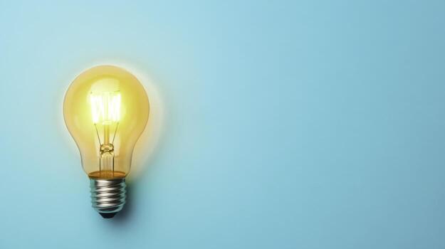 Bright Yellow Light Bulb Against Soft Turquoise Background for Creative Ideas photo