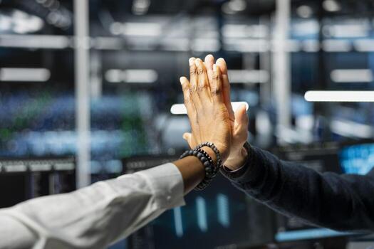 Close up of data center employees doing high five after upgrade systems using AI tech. IT workers celebrating achievement in server room, finishing deep learning checkup on hardware rigs photo