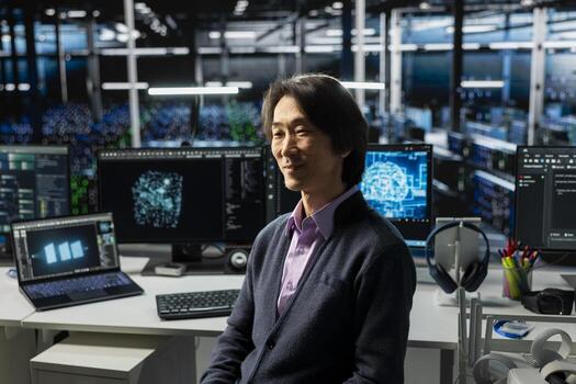 Smiling server hub senior programmer using devices to monitor neural network with AI LLM. Asian man at work in data center using artificial intelligence to oversee servers powering machine learning photo