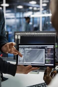 Close up of data center IT staff members coding on tablet, deploying servers. Team of programmers using device in server room, doing brainstorming, managing large scale IT infrastructure rackmounts photo