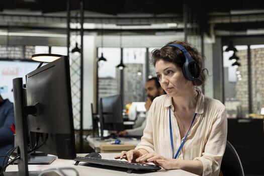 Female manager in a modern office space works with podcast on headset, developing a new business strategy based on analytics. Reports to align objectives with corporate performance results. photo