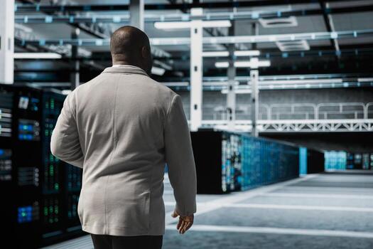 System administrator doing yearly checkup to prolong data center hardware life span and avoid downtime. African american server farm worker monitoring server infrastructure components photo
