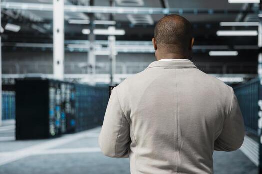 Engineer in data center updating systems, protecting hardware equipment from damaging software vulnerabilities. Server farm worker looking for bugs causing infrastructure to slow down photo