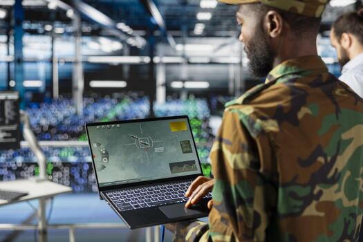 Black military IT expert in server hub using AI tools to oversee battlefield surveillance to develop warfare tactics. Army data center admin doing transmission analysis and live monitoring. photo