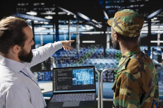 African american army technician uses neural network for defense systems, working with an engineer in server farm. Drone operators in military data center doing live drone tracking on laptop. photo