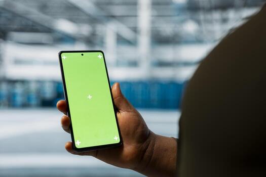 Close up of data center admin using green screen smartphone to monitor infrastructure network performance. Server room employee checks gear functionality using mockup mobile phone photo