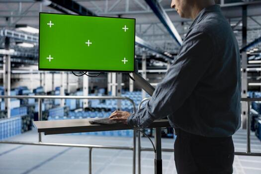Server farm IT expert uses mockup computer, managing infrastructure resources. Data center admin using green screen PC monitor, configuring server settings for improved reliability and uptime photo