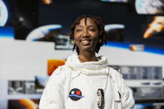 Cheerful astronaut inside high tech spacecraft preparing for scientific mission. Jolly spaceship crew member in advanced spacesuit looking at planetary exploration data on digital videowall photo