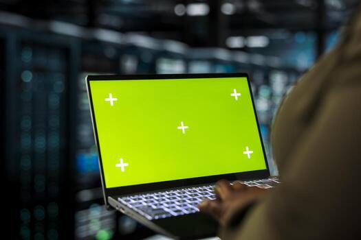 Close up of programmer using green screen laptop in data center to track metrics of gear used to host websites. Server hub worker upgrading rigs running companies databases using mockup notebook photo