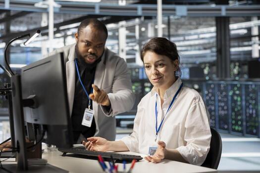 Data center manager supervising work done by engineer updating servers tech, configuring gear using software. Server hub supervisor overseeing worker reviewing hardware analytics photo