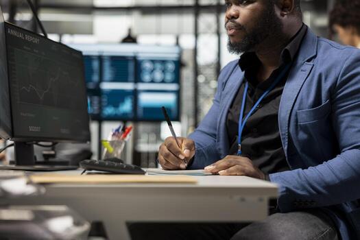 Male general manager does project planning with notes on a notepad, extracting data from online forecast. Expert focusing on organizational success and obtaining more capital funds. photo